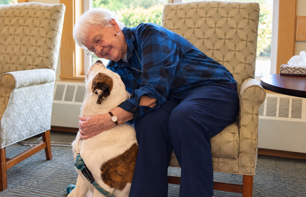 Resident sharing a moment with a visiting dog at Legacy Court Senior Living in Spokane, Washington